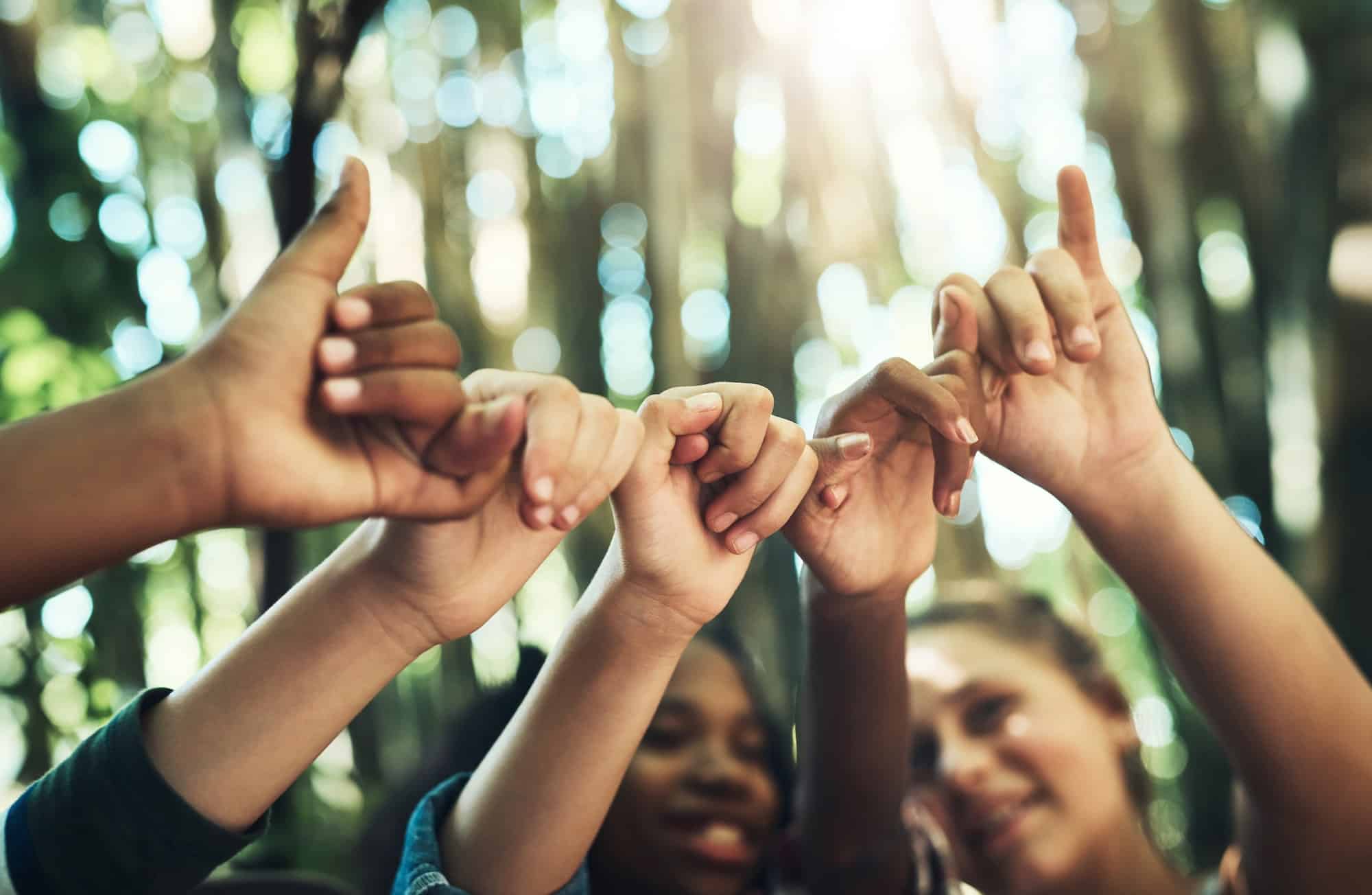 Shot of a group of teenagers linking fingers at summer camp
